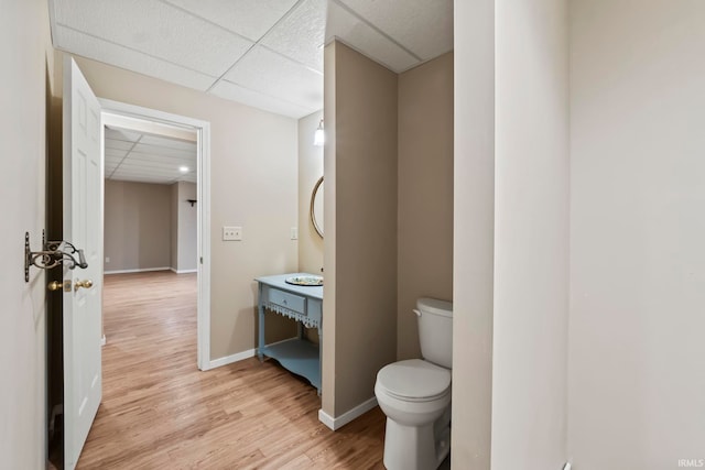 bathroom with a drop ceiling, hardwood / wood-style floors, and toilet