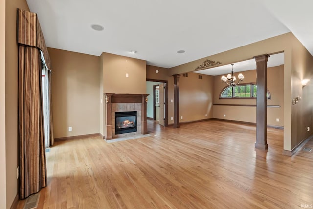 unfurnished living room featuring a tile fireplace, a chandelier, and light hardwood / wood-style flooring