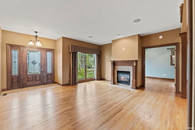 entryway with a tile fireplace, light hardwood / wood-style flooring, and a notable chandelier