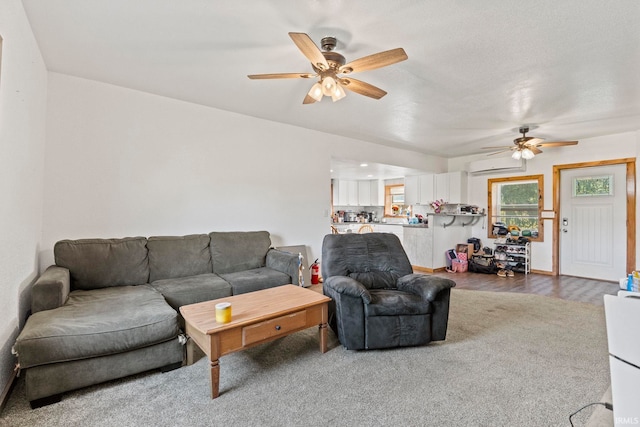 living room featuring dark wood-type flooring, ceiling fan, and a wall unit AC