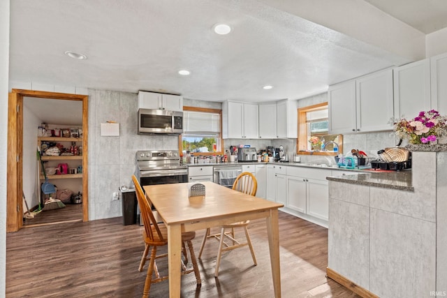 kitchen with white cabinets, stainless steel appliances, a textured ceiling, hardwood / wood-style flooring, and sink