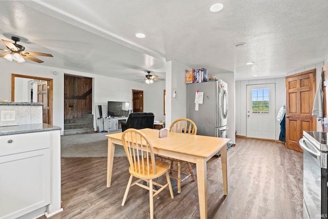 dining space featuring light wood-type flooring, a textured ceiling, and ceiling fan