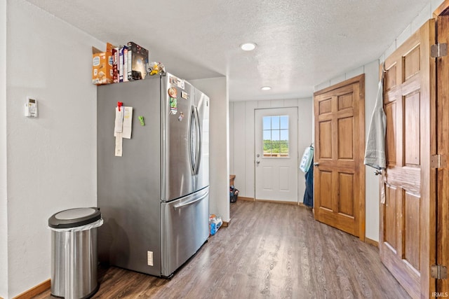 kitchen with a textured ceiling, stainless steel refrigerator, and wood-type flooring