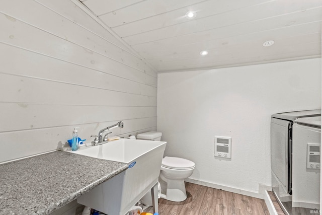 bathroom with lofted ceiling, washing machine and clothes dryer, heating unit, hardwood / wood-style flooring, and toilet