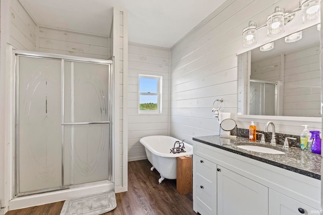 bathroom with independent shower and bath, vanity, wood walls, and wood-type flooring