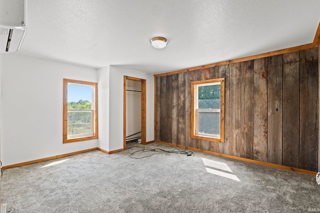 unfurnished bedroom featuring wood walls, a textured ceiling, and carpet floors