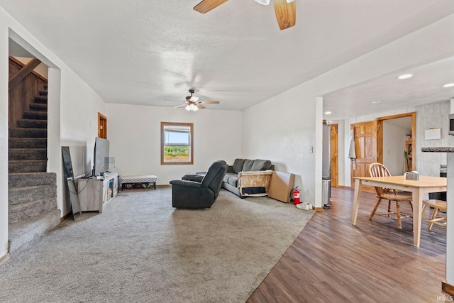 living room featuring ceiling fan, hardwood / wood-style flooring, and a textured ceiling