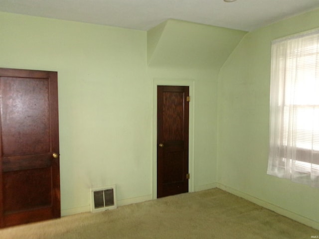 unfurnished bedroom with light colored carpet and lofted ceiling