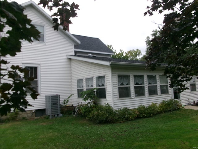 rear view of property featuring cooling unit and a lawn