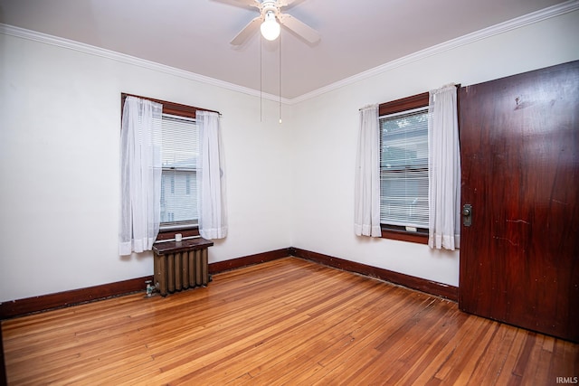 spare room featuring ceiling fan, radiator, hardwood / wood-style flooring, and crown molding