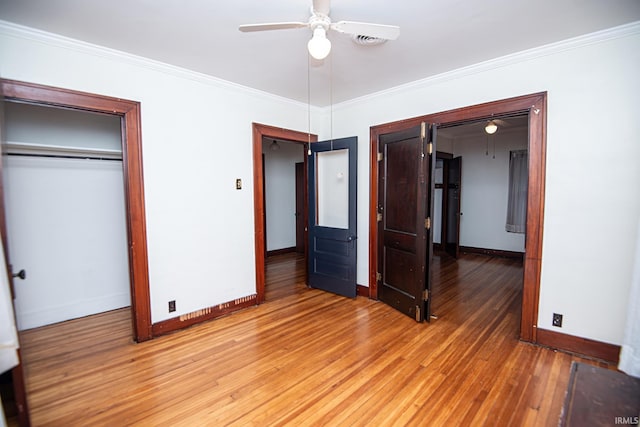 unfurnished bedroom with ornamental molding, ceiling fan, a closet, and hardwood / wood-style flooring