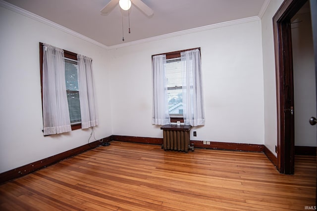 empty room featuring ceiling fan, crown molding, light hardwood / wood-style floors, and radiator heating unit