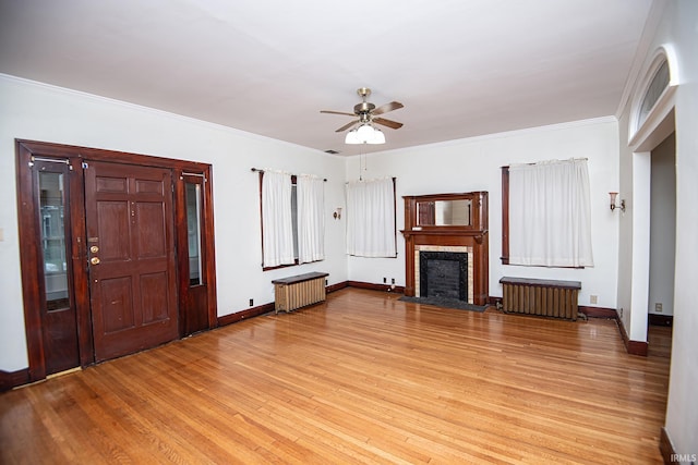 unfurnished living room featuring ceiling fan, light wood-type flooring, crown molding, and radiator heating unit