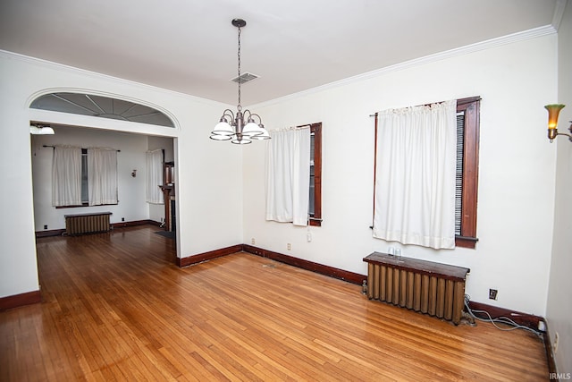 unfurnished room with crown molding, radiator, hardwood / wood-style floors, and a chandelier