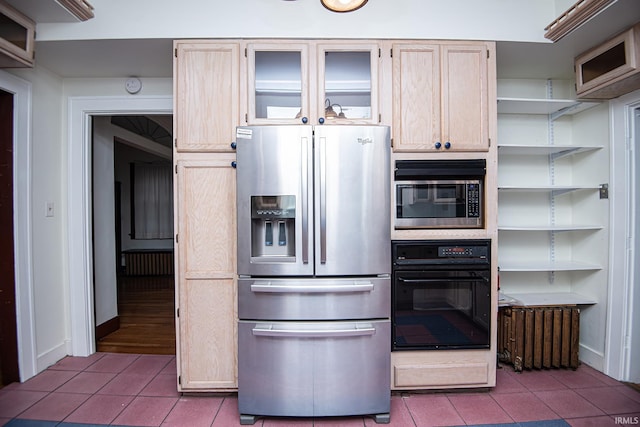 kitchen with appliances with stainless steel finishes, radiator, light brown cabinetry, and light tile patterned floors