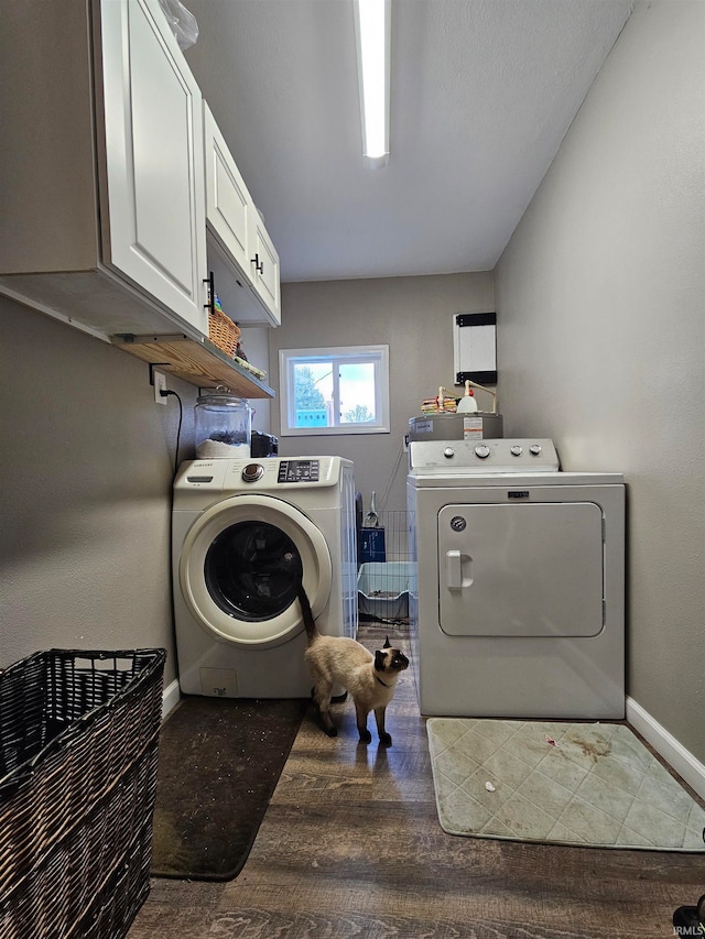 laundry room with wood-type flooring, washing machine and dryer, and cabinets