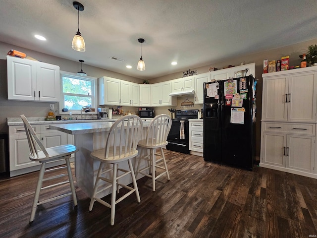 kitchen with decorative light fixtures, dark wood-type flooring, white cabinetry, and black appliances