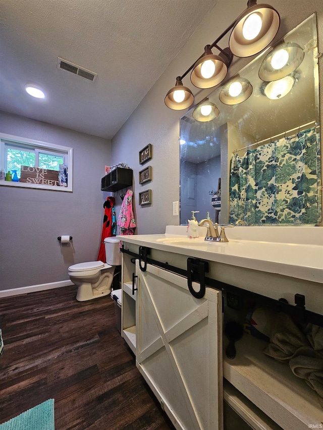bathroom featuring a textured ceiling, hardwood / wood-style flooring, vanity, and toilet