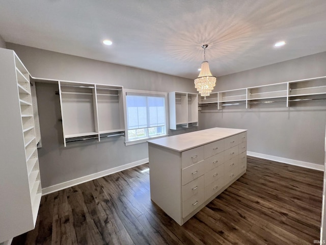 spacious closet with dark hardwood / wood-style floors and a chandelier