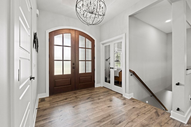 foyer entrance with french doors, an inviting chandelier, and light hardwood / wood-style floors