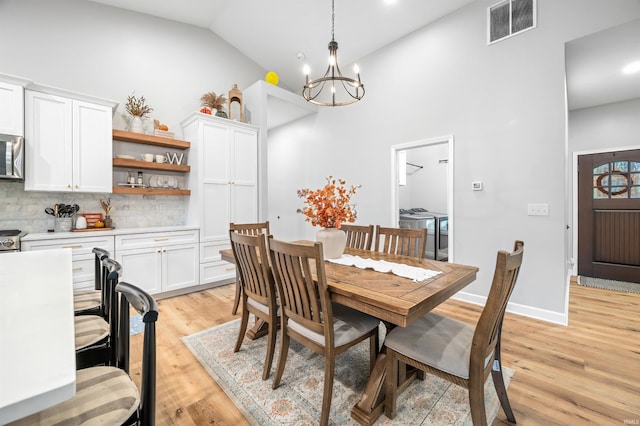 dining room with a notable chandelier, light hardwood / wood-style flooring, and high vaulted ceiling