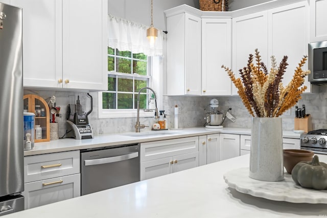 kitchen with tasteful backsplash, sink, white cabinetry, hanging light fixtures, and stainless steel appliances