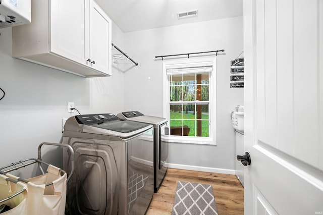 washroom with water heater, light hardwood / wood-style flooring, independent washer and dryer, and cabinets