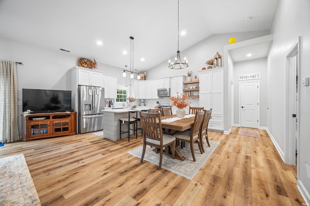 dining space with an inviting chandelier, light wood-type flooring, and lofted ceiling