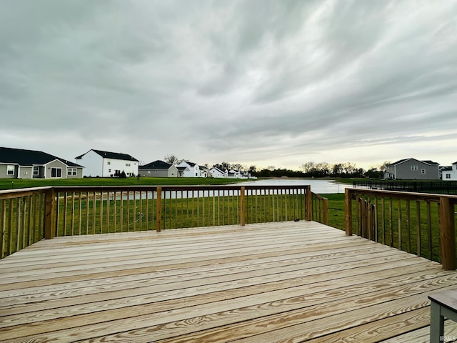 wooden deck featuring a lawn and a water view