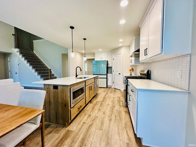 kitchen with sink, decorative light fixtures, a kitchen island with sink, white cabinetry, and stainless steel appliances