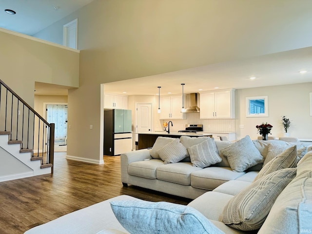 living room with a high ceiling, sink, and hardwood / wood-style flooring