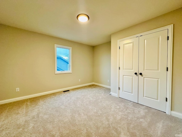 unfurnished bedroom featuring light colored carpet and a closet