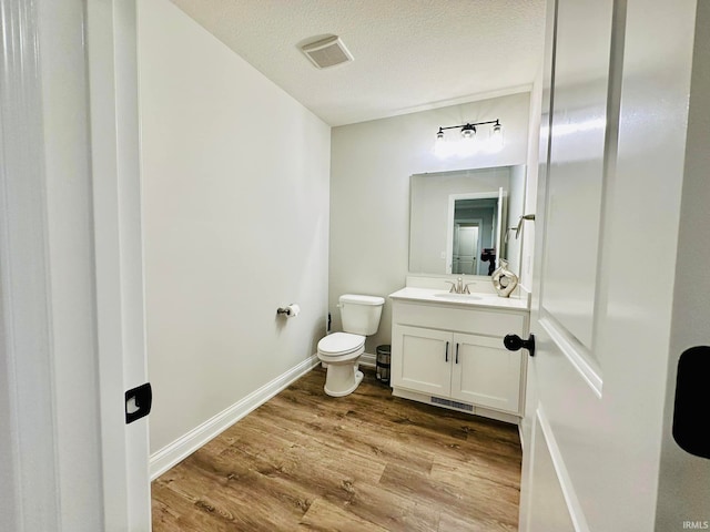 bathroom with a textured ceiling, vanity, toilet, and hardwood / wood-style flooring