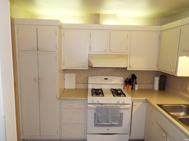 kitchen featuring backsplash, white cabinetry, sink, and white gas stove