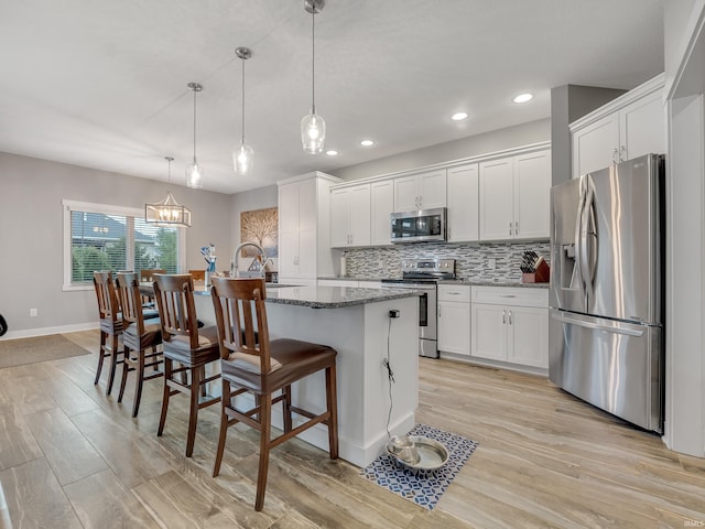 kitchen featuring an island with sink, white cabinetry, light hardwood / wood-style flooring, and stainless steel appliances