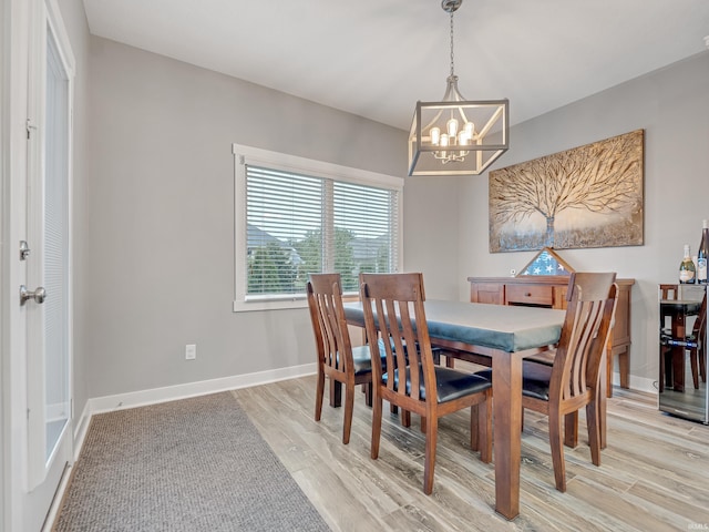 dining room with light wood-type flooring and an inviting chandelier