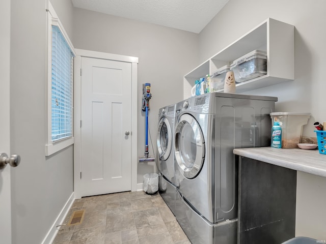 laundry area with a textured ceiling and washing machine and dryer