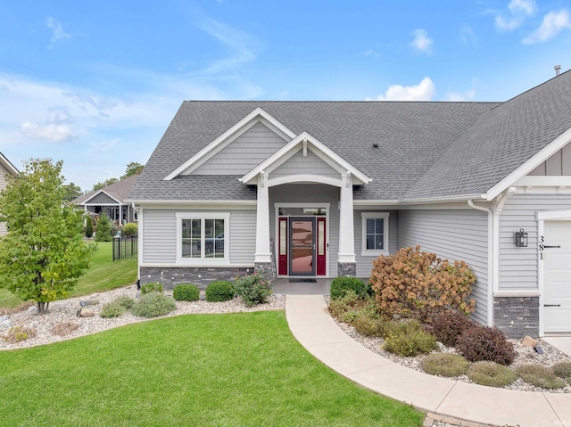 381 Elderwood Ct, Fort Wayne, IN 46845 - craftsman house featuring a front yard, roof with shingles, stone siding, and an attached garage
