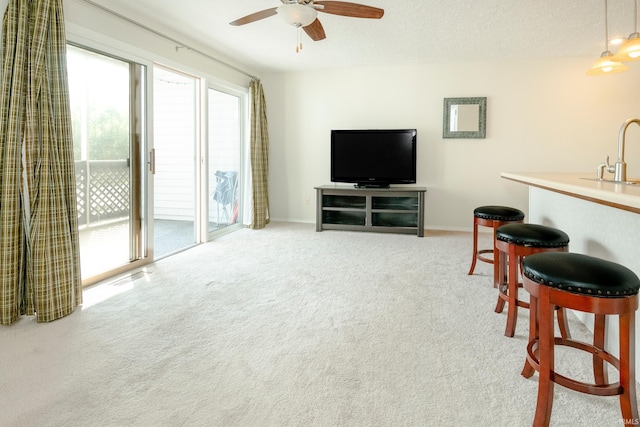 carpeted living room featuring ceiling fan, wet bar, and a textured ceiling