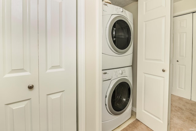 clothes washing area with stacked washer / dryer and light colored carpet