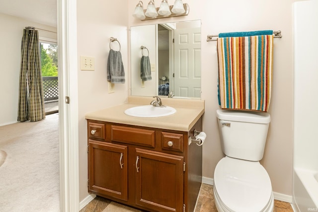 bathroom with a tub to relax in, vanity, and toilet