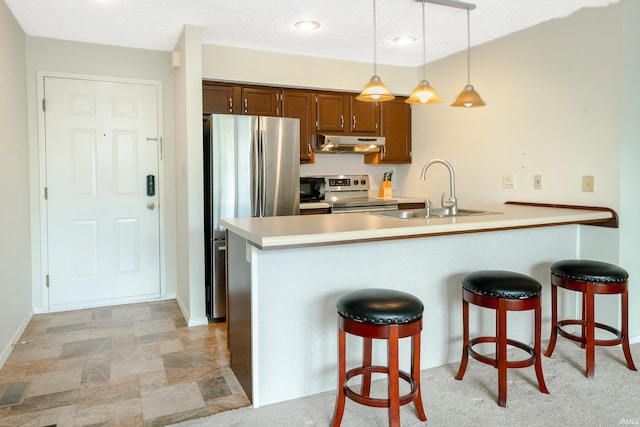 kitchen with pendant lighting, sink, kitchen peninsula, appliances with stainless steel finishes, and a kitchen breakfast bar