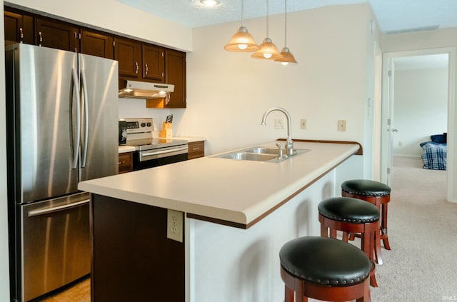 kitchen featuring a kitchen breakfast bar, stainless steel fridge, hanging light fixtures, electric range oven, and sink