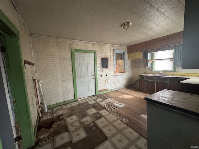 kitchen featuring sink and brick wall