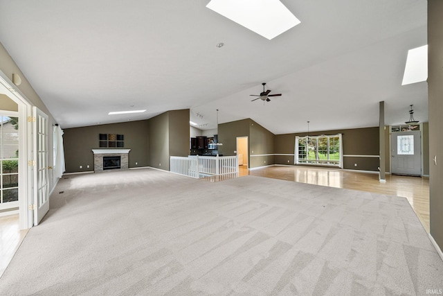 unfurnished living room with ceiling fan, light colored carpet, and lofted ceiling