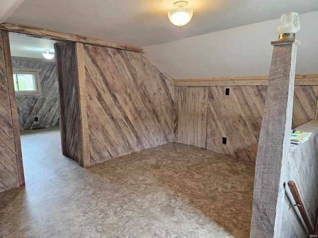 bonus room with wood walls and vaulted ceiling