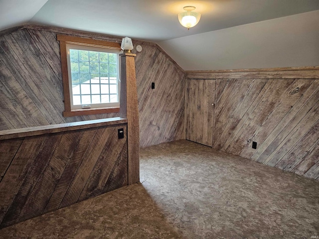 additional living space featuring wood walls, carpet, and vaulted ceiling