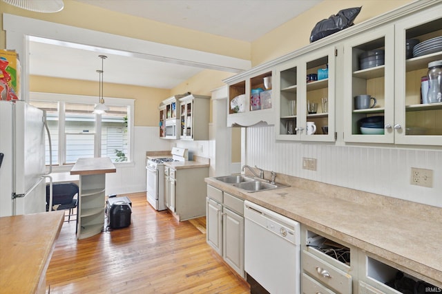 kitchen with pendant lighting, white appliances, light hardwood / wood-style floors, and sink