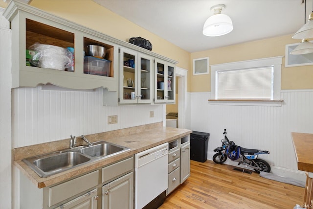 kitchen featuring light wood-type flooring, washer / dryer, sink, decorative light fixtures, and white dishwasher