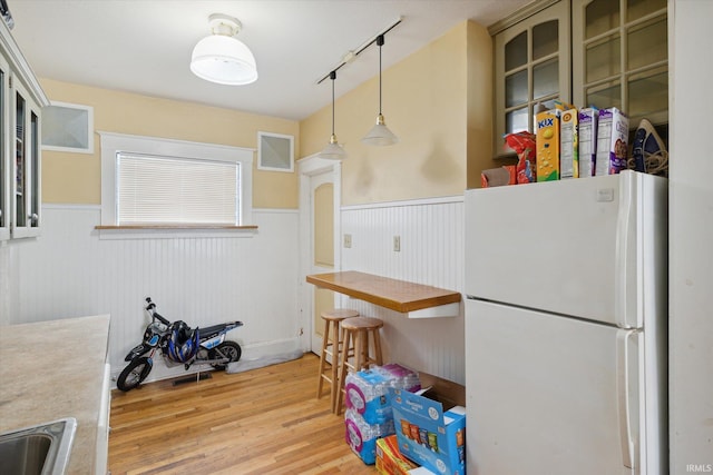 kitchen featuring track lighting, light hardwood / wood-style floors, hanging light fixtures, and white fridge